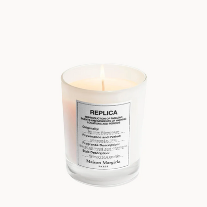 A Maison Margiela REPLICA scented candle in a clear glass jar with a white label, set against a plain white background.
