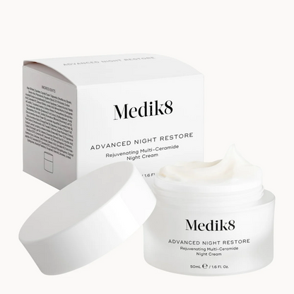 Medik8 Advanced Night Restore night cream jar with its lid off, placed in front of its white product box on a clean white background.