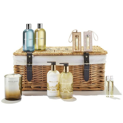 Molton Brown Cosmetic set with wicker basket, EDP fragrances, skincare products, and candles on a white background