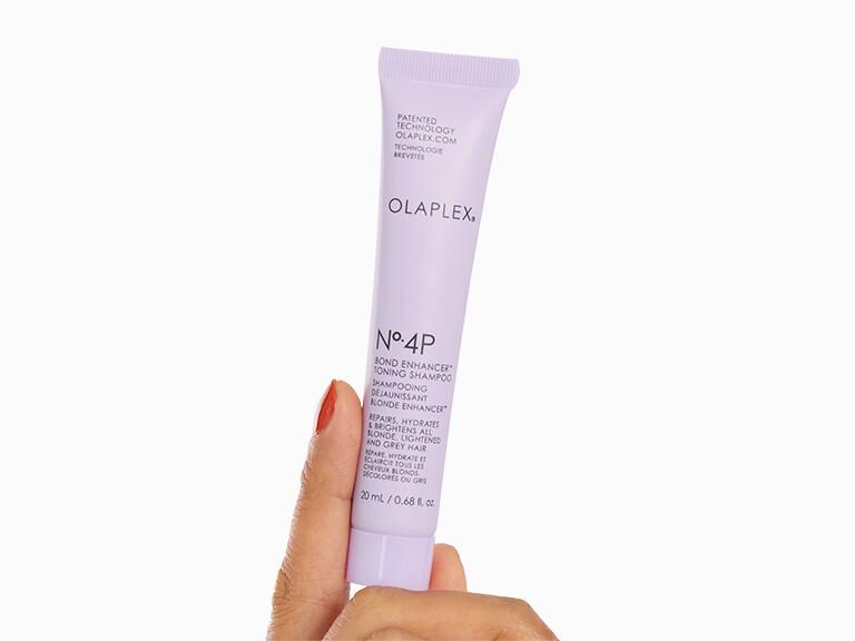 Hand holding a tube of Olaplex No.4P on a white background