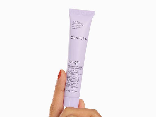 Hand holding a tube of Olaplex No.4P on a white background