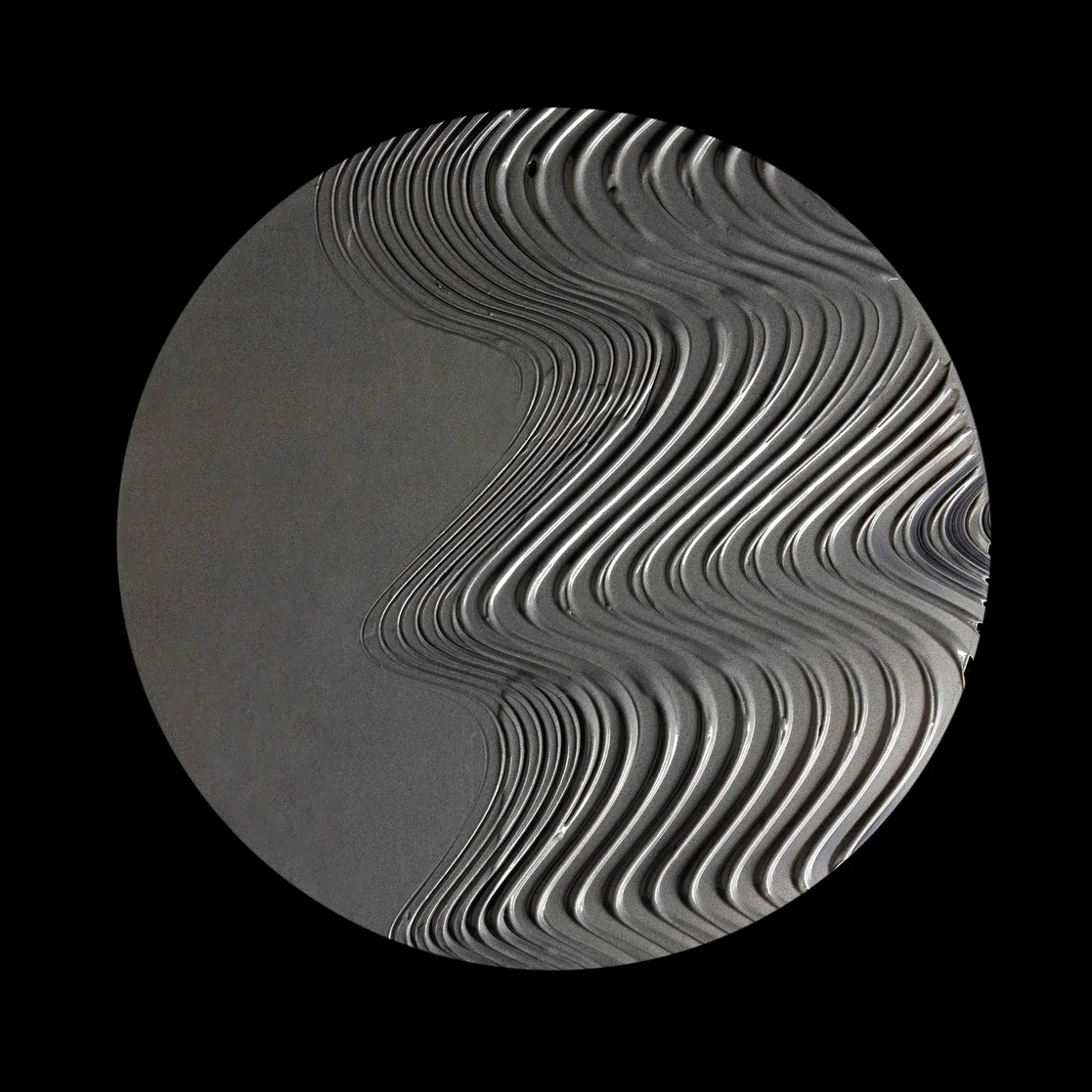 A circular abstract representation of mud mask featuring layered, wavy concentric lines in shades of gray and white on a black square background, centered within a light gray border.