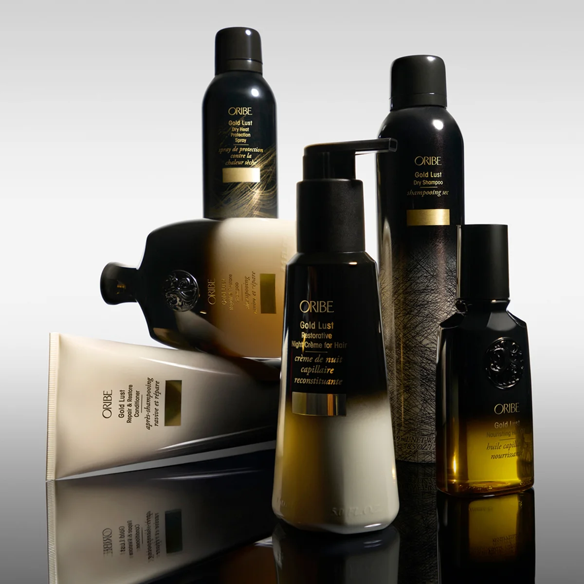 Oribe hair care products on a reflective surface with a gray background