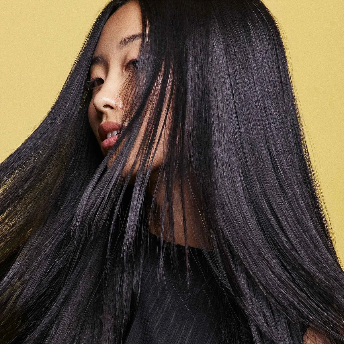 Woman with long black hair against a yellow background