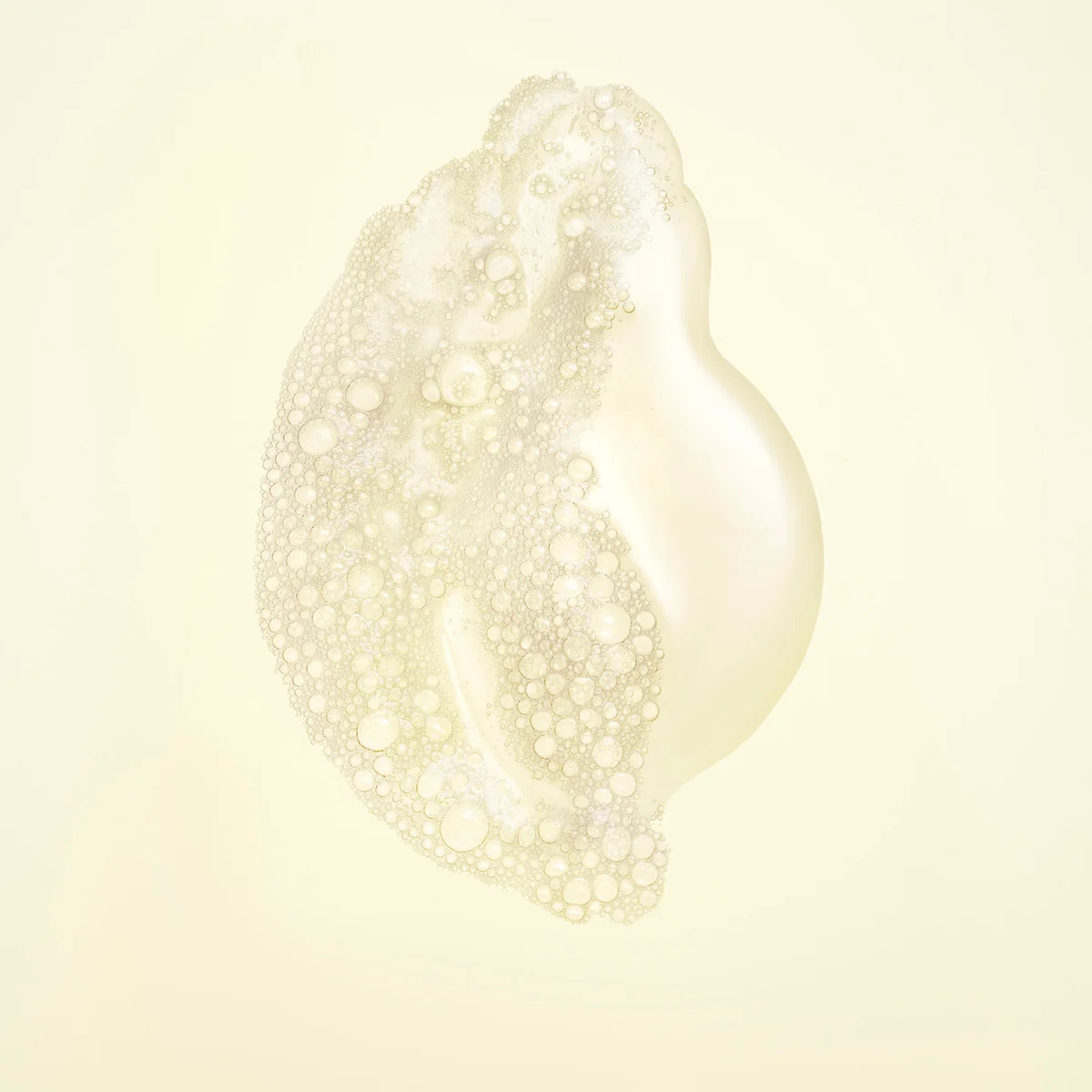 A single translucent, pearlescent droplet or blob with dense bubble texture on a soft cream background.