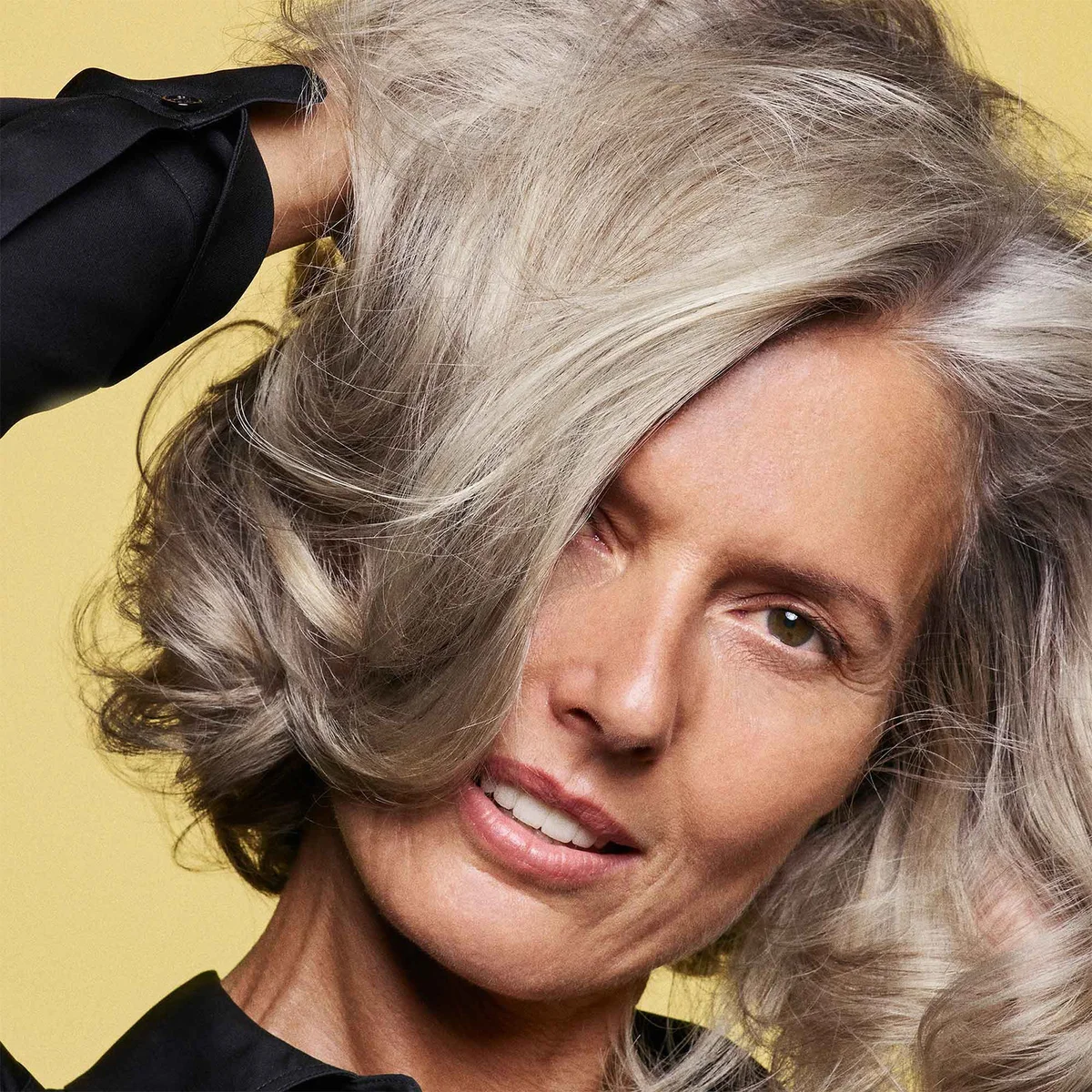 Woman with gray hair against a yellow background