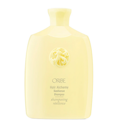 A pale yellow bottle of ORIBE Hair Alchemy Resilience Shampoo on a solid white background.