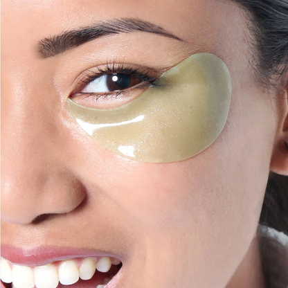 A close-up of a woman's face showing a glossy, pale green eye patch applied under her left eye.