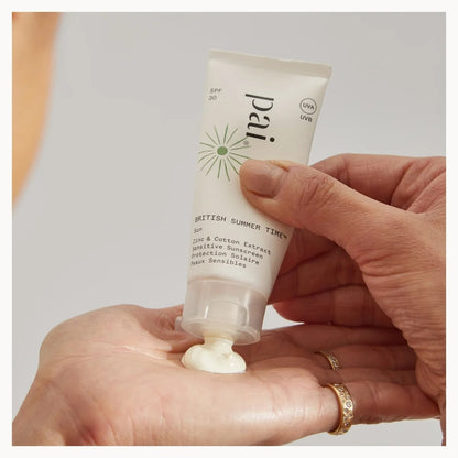 Hand holding a tube of Pai skincare product with cream on the palm against a neutral background