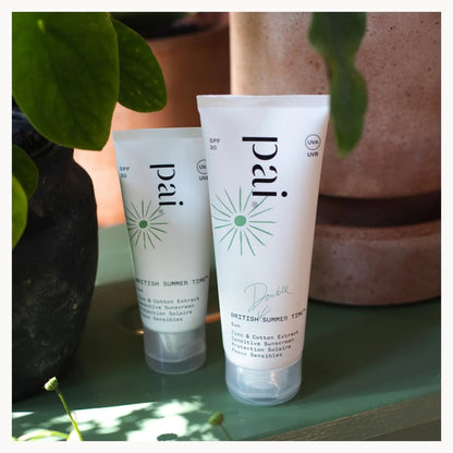 Two 'pai' skincare products on a surface with plants in the background