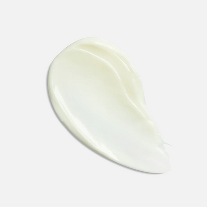 A smooth, creamy swatch of off-white lotion or cream with a glossy finish, presented on a clean, light gray background.