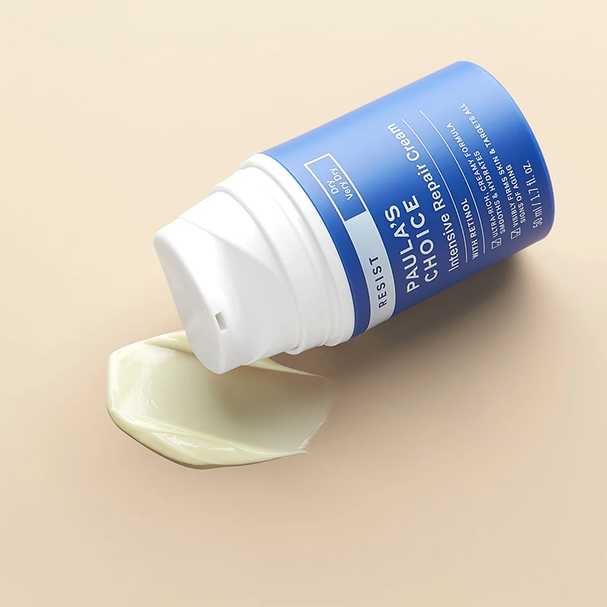 A blue and white pump bottle of Choilae Repair Cream lies on its side with a dollop of pale yellow cream spilled in front, set against a solid beige background.