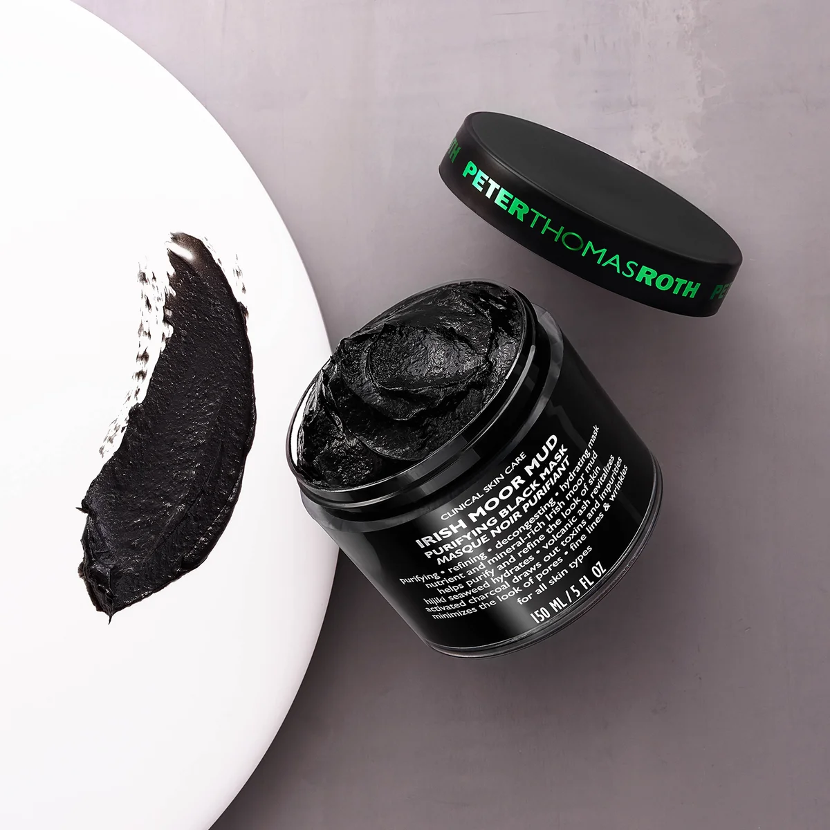Black facial mask in a jar with 'Peter Thomas Roth' branding on a gray background
