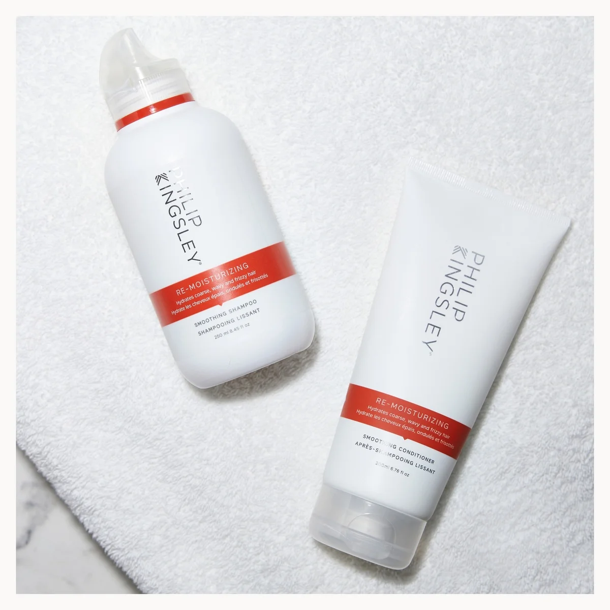 Two bottles of Philip Kingsley hair products on a white towel