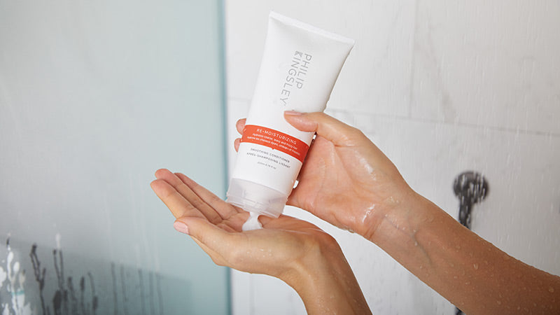 Person holding a tube of CeraVe skincare product in a bathroom setting
