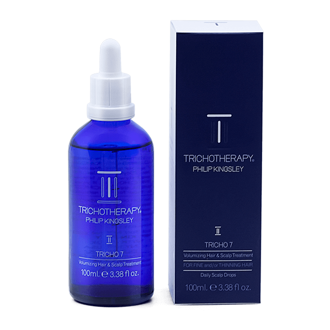 Blue bottle and packaging of Tricho7 Philip Kingsley hair care product on a black background