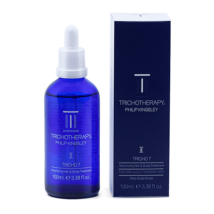 Blue bottle and packaging of Tricho7 Philip Kingsley hair care product on a black background