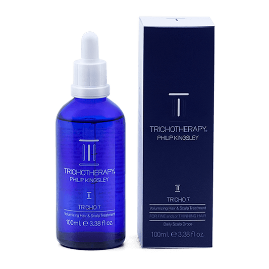 Blue bottle and packaging of Tricho7 Philip Kingsley hair care product on a black background