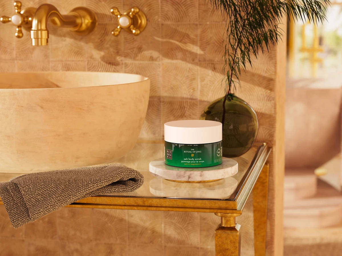 Cosmetic jar on a marble surface in a bathroom with a bathtub and decorative elements.