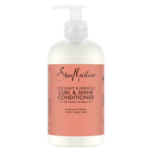 A bottle of SheaMoisture Coconut & Hibiscus Curl & Shine Conditioner with a white pump dispenser and a coral pink label, shown against a plain white background.