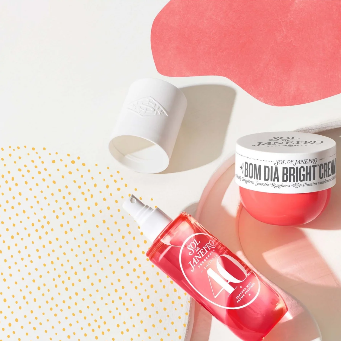 A flat-lay product shot of a red and white Dr. Jack's '80M Dia Bright Cream set, featuring a red spray bottle and a white cream jar with its cap off, styled on a white background with abstract pink and yellow polka-dot paper shapes.