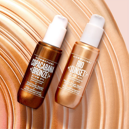 Two bottles of Euphoric Cosmetics glow oil, one labeled 'Copacabana + Bronze' in a dark bronze bottle and the other labeled 'Rio Sunset + Gold' in a lighter gold bottle, set against a metallic rose-gold wavy background.