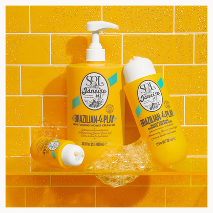Three yellow sol de janeiro Brazilian-4-Play hair care bottles arranged on a clear shelf against a yellow tiled background with water droplets and foam.