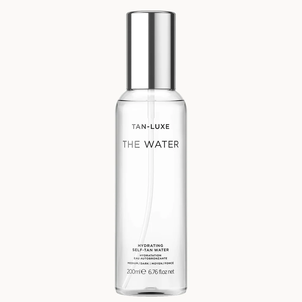 A clear cylindrical bottle of Tan-Luxe 'The Water' hydrating self-tan water with a reflective silver cap, centered on a light gray background.