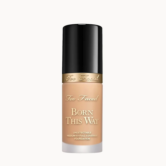 Too Faced Born This Way liquid foundation in a clear bottle showing the beige foundation shade, topped with a black cap and a gold band.