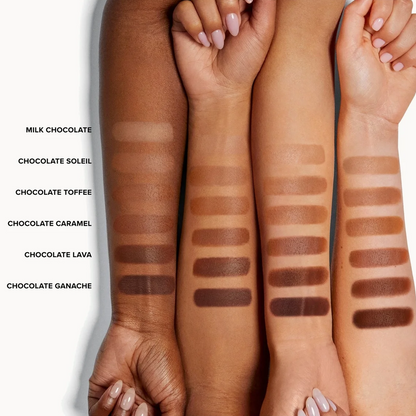 Five swatches of makeup applied on forearms, labeled from left to right as Milk Chocolate, Chocolate Soleil, Chocolate Toffee, Chocolate Caramel, and Chocolate Lava, with Chocolate Ganache also shown. The swatches are displayed on multiple arms with different skin tones against a white background.