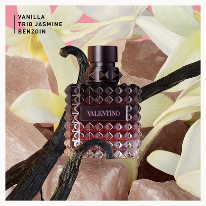 Valentino Born in Roma Donna Intense Eau de Parfum for Her 30ml Vanilla Trio Jasmine Benzoin perfume bottle in a textured dark glass design, surrounded by vanilla beans, pink crystals, and pale yellow flowers. The text 'VANILLA TRIO JASMINE BENZOID' is visible in the top left corner.
