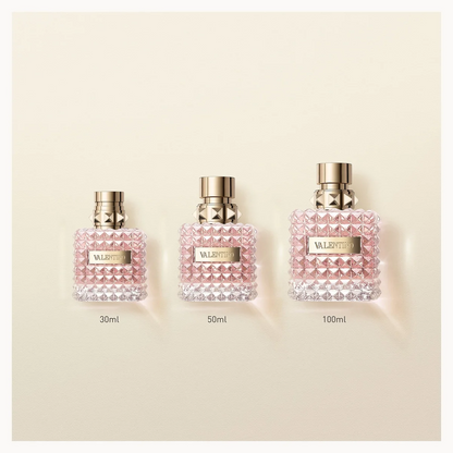 Three Valeria Rossi perfume bottles in 30ml, 50ml, and 100ml sizes lined up on a light beige background. The bottles are clear with a textured pink and white beaded pattern, topped with gold caps, and feature a gold brand label.
