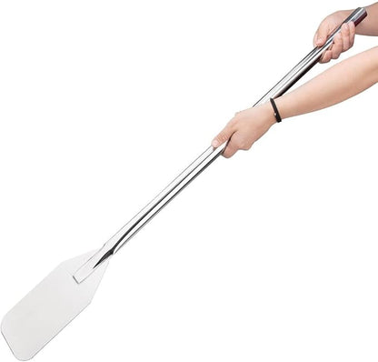 Person holding a metal long food mixing paddle on a white background