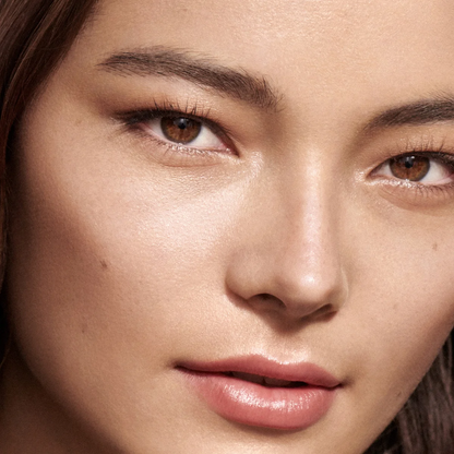 Close-up of a woman's face with natural, matte pink lipstick on her lips and subtle eyeshadow.