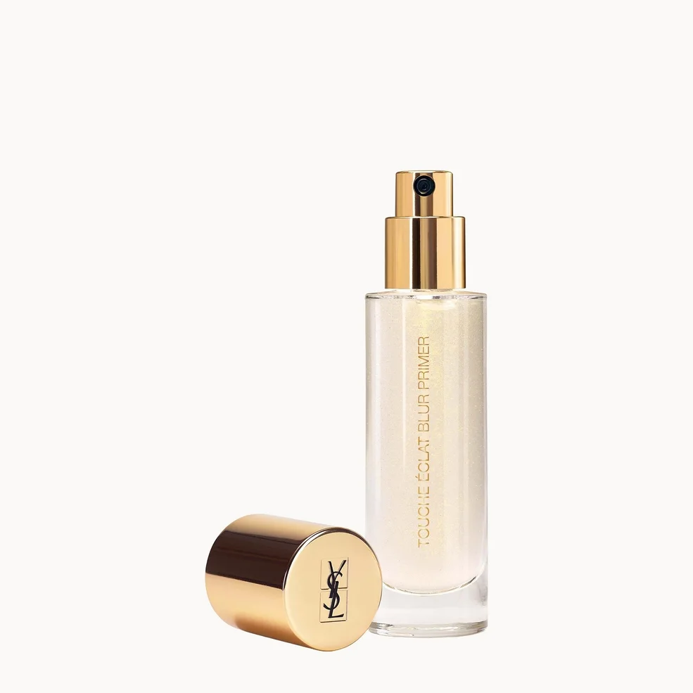 YSL Touche de Nuit Primer in a clear cylindrical bottle with a gold pump, shown next to its gold cap on a light off-white background.