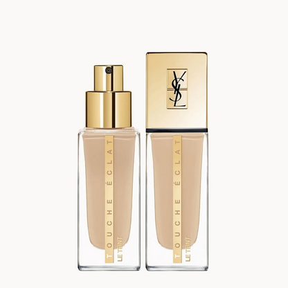 YSL Touche Eclat Liquid Foundation in a clear rectangular bottle with a gold pump, shown next to its gold cap on a light gray background.