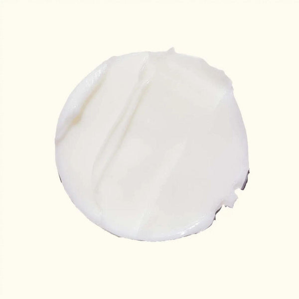 A dollop of thick, creamy white cosmetic cream or lotion on a solid off-white background.