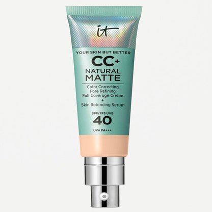 It Cosmetics CC+ Natural Matte Color Correcting Full Coverage Cream in a squeeze tube with a metallic teal body, a beige lower section, and a silver pump dispenser, shown against a plain off-white background.