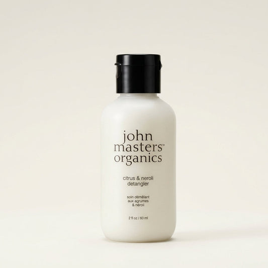 A 2 fl oz bottle of John Masters Organics Citrus & Neroli Detergent, featuring a matte white bottle and a black screw cap, set against a solid off-white background.