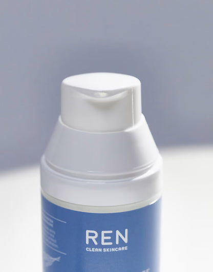 A close-up of a REN Clean Skincare pump bottle with a white cap and a blue label, set against a soft gray background.